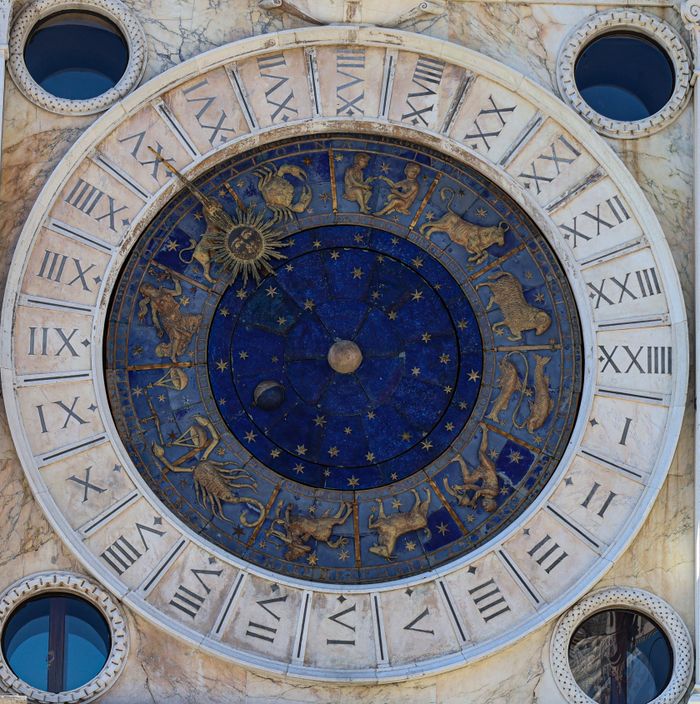 Home A detailed view of the historic astrological clock in Venice, featuring zodiac signs and Roman numerals.