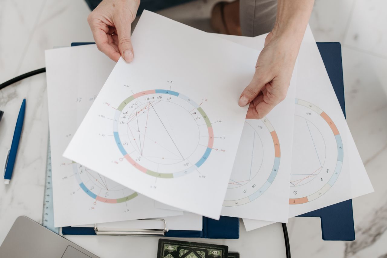 Home Hands holding astrological charts and graphs, symbolizing horoscopes and fortune-telling.